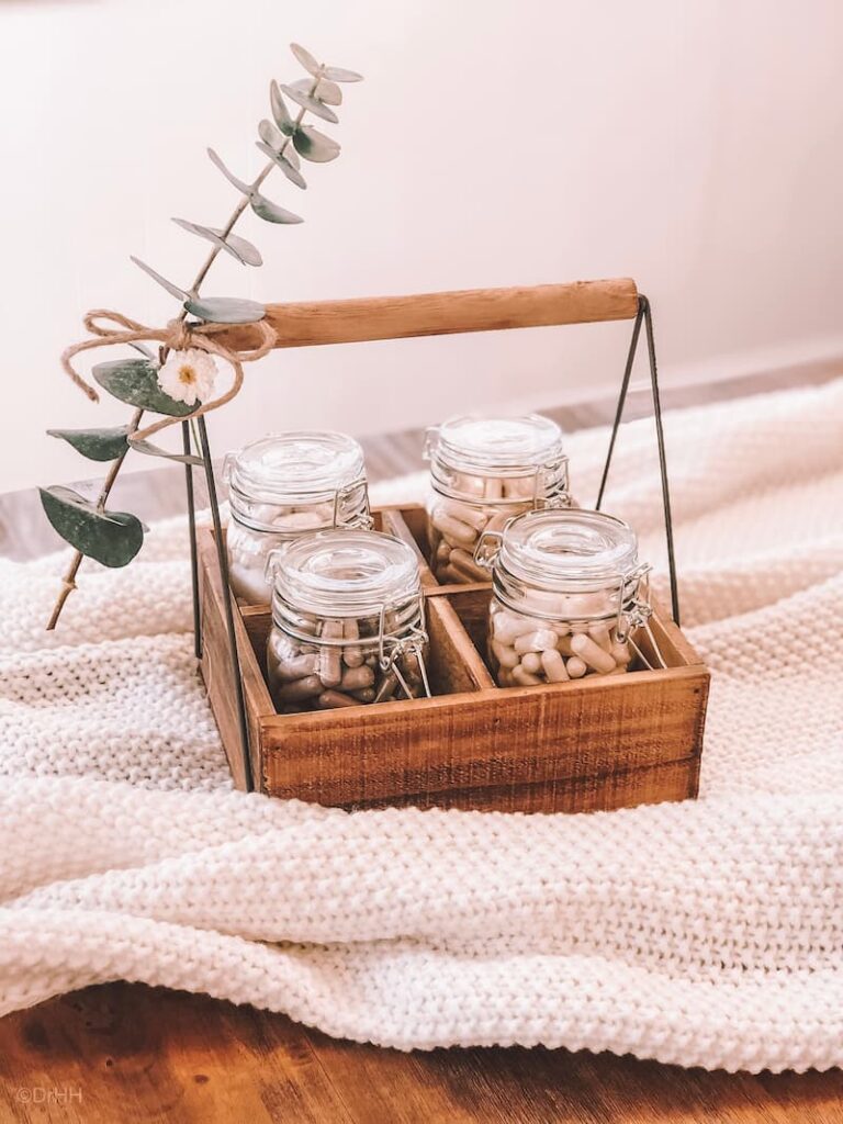 Supplements in mason jars in wooden box with eucalyptus decoration