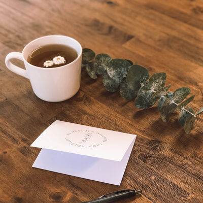 Notecard and cup of tea with eucalyptus on wooden table